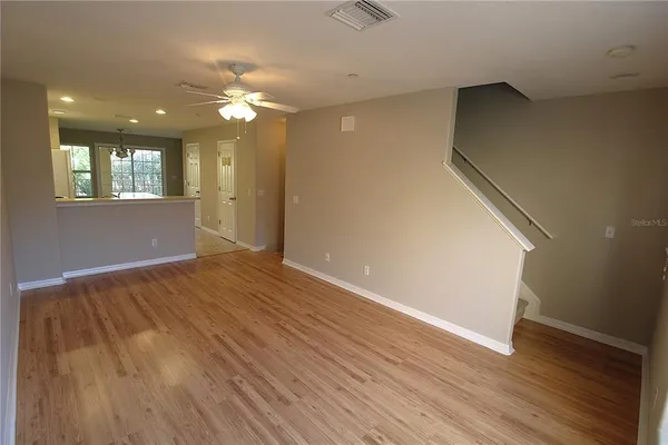 a view of empty room with wooden floor and fan