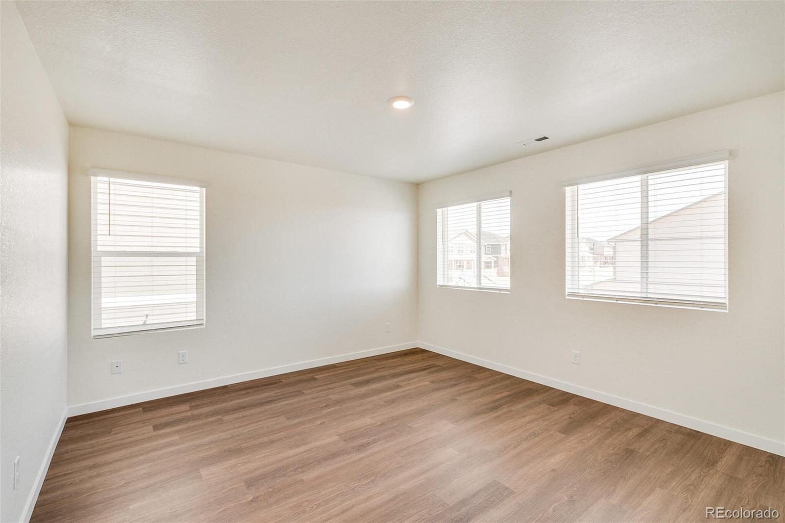 6907 Zig Place Frederick, CO 80530 - Photo 17 of 36 an empty room with wooden floor and windows