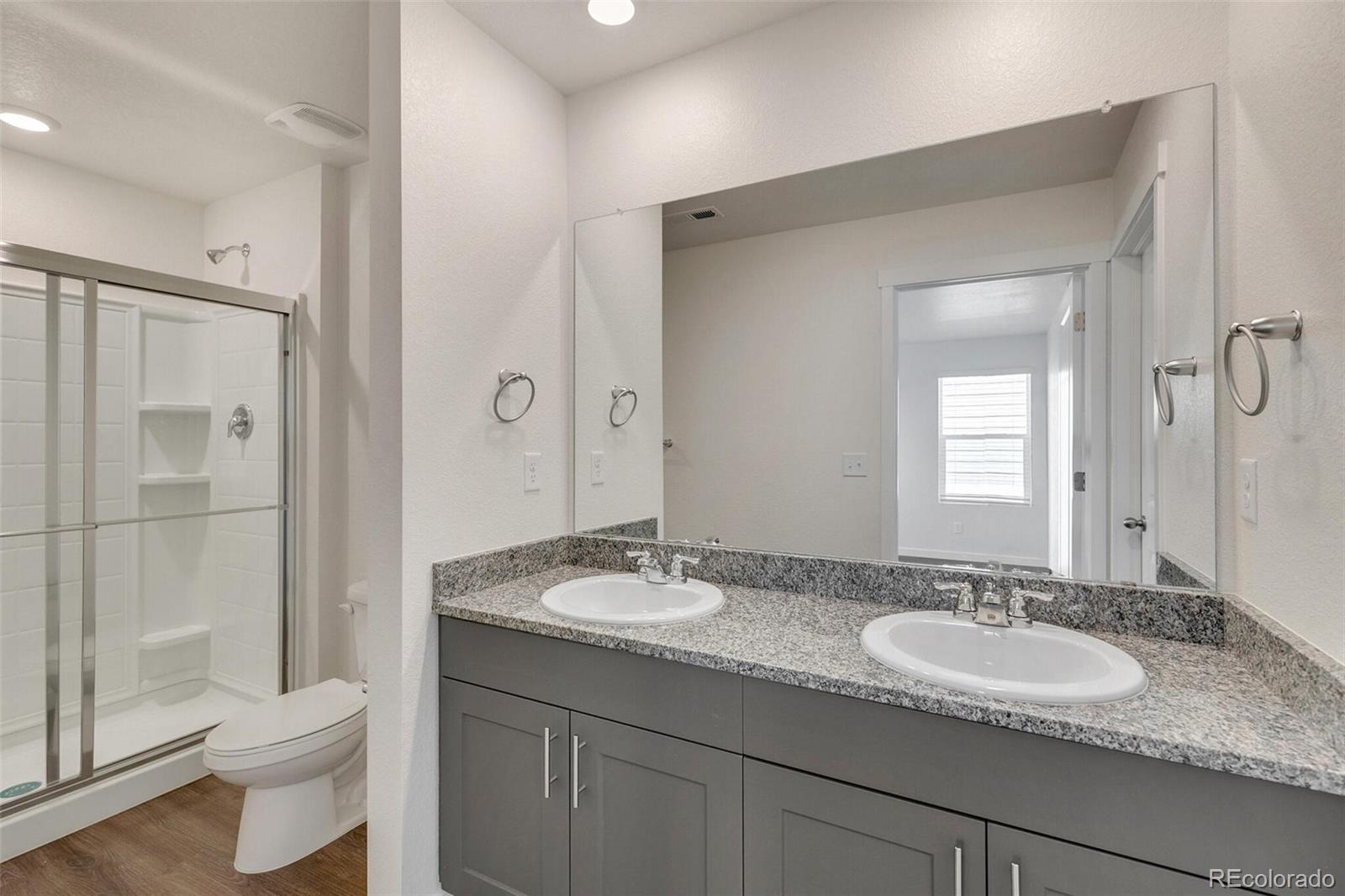 6907 Zig Place Frederick, CO 80530 - Photo 19 of 36 a bathroom with a granite countertop sink toilet and shower
