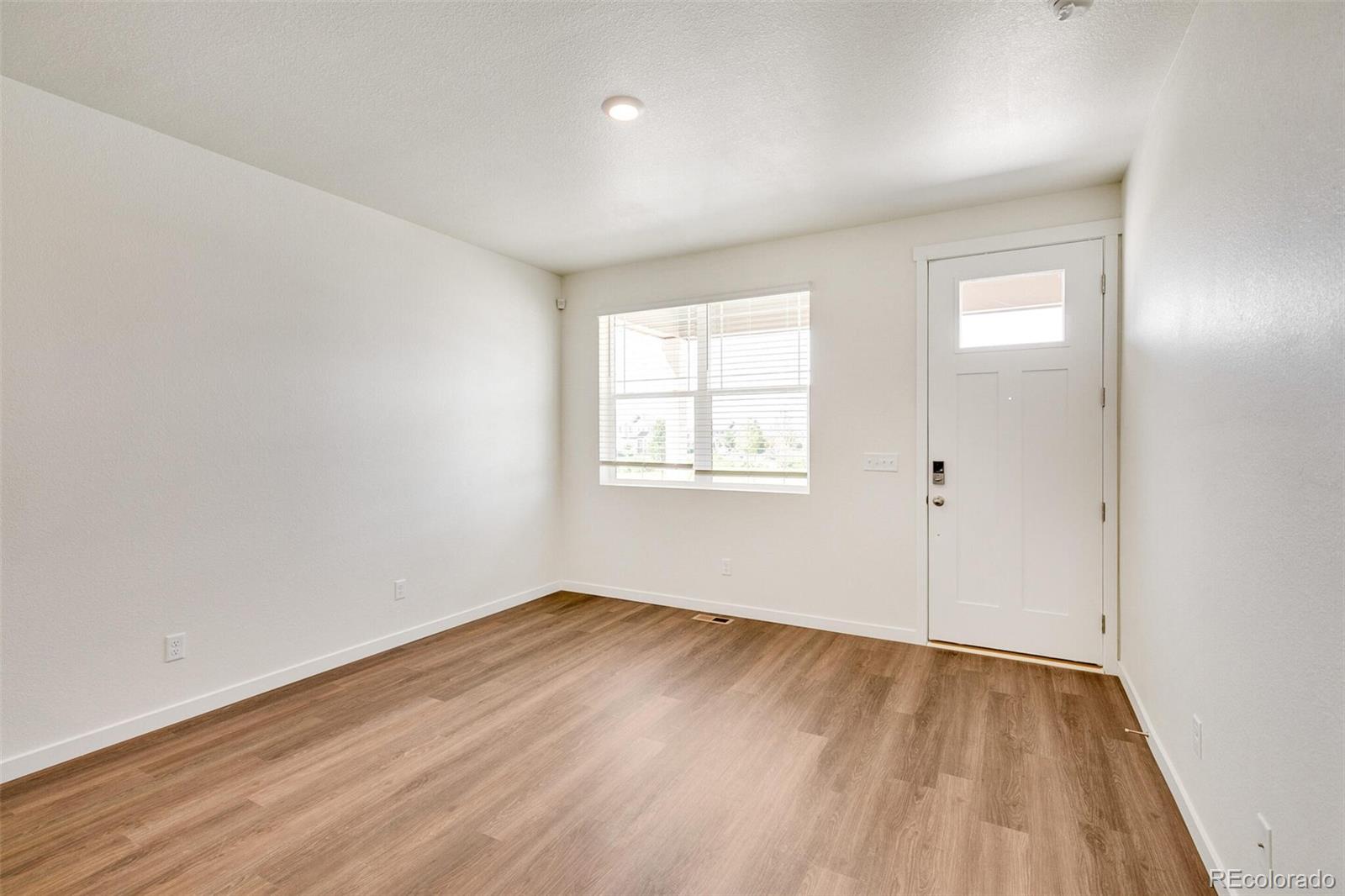 6907 Zig Place Frederick, CO 80530 - Photo 7 of 36 an empty room with wooden floor and windows