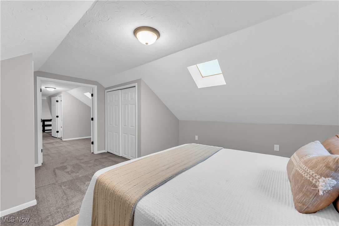 6920 Joppa Road Vermilion, OH 44089 - Photo 26 of 38 Bedroom with a closet, vaulted ceiling with skylight, and carpet floors