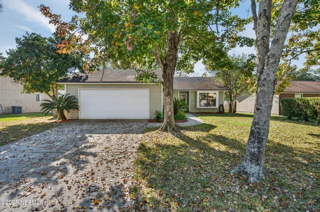 a view of a house with a yard and large tree