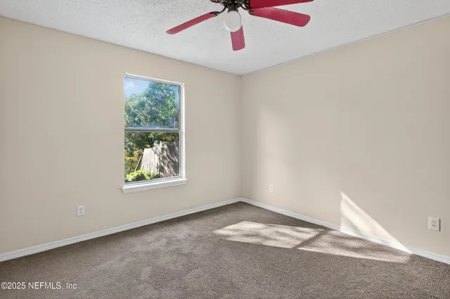 an empty room with windows and fan