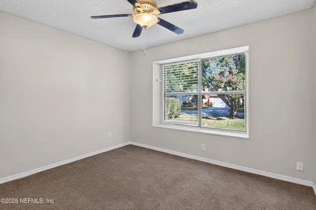 an empty room with a window and a fan