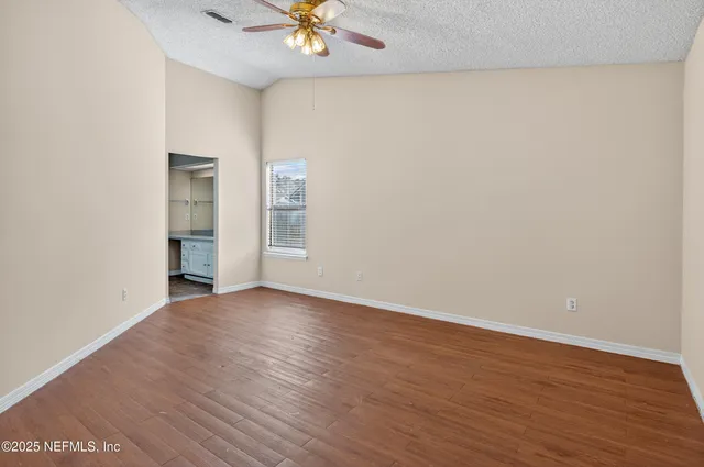 an empty room with wooden floor and natural light