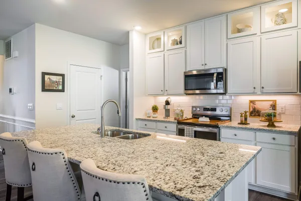 a kitchen with granite countertop a stove a microwave a sink and cabinets