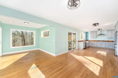 a view of a livingroom with wooden floor a ceiling fan and windows