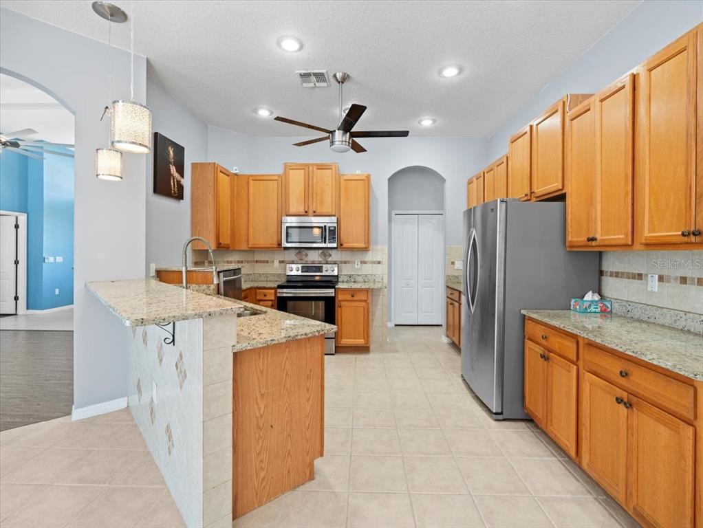 10307 Ridge Top Loop Weeki Wachee, FL 34613 - Photo 14 of 50 a kitchen with stainless steel appliances a refrigerator stove microwave and sink