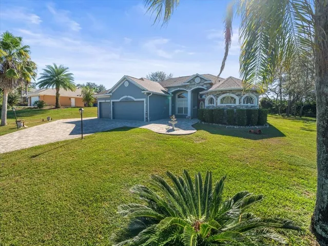 a front view of a house with a yard and palm trees