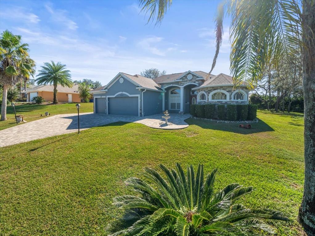 10307 Ridge Top Loop Weeki Wachee, FL 34613 - Photo 2 of 50 a front view of a house with a yard and palm trees