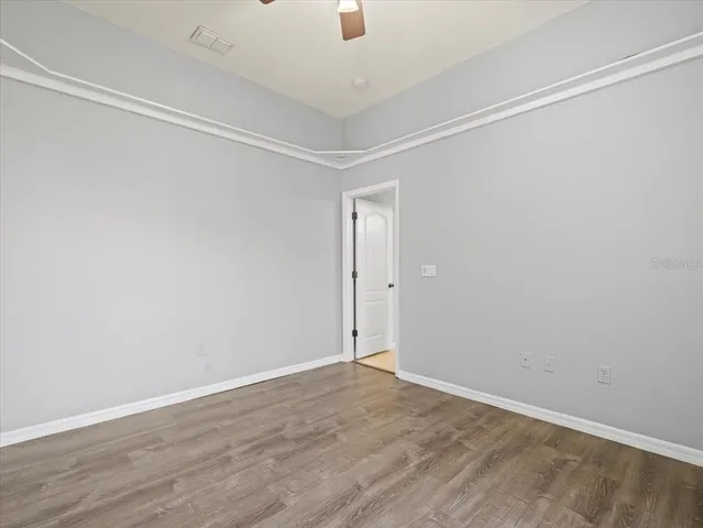 an empty room with wooden floor closet fan and windows