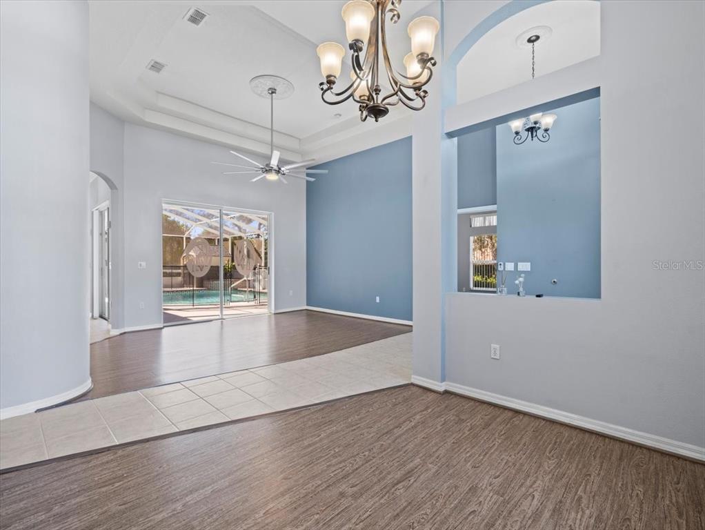 10307 Ridge Top Loop Weeki Wachee, FL 34613 - Photo 7 of 50 an empty room with wooden floor chandelier and windows