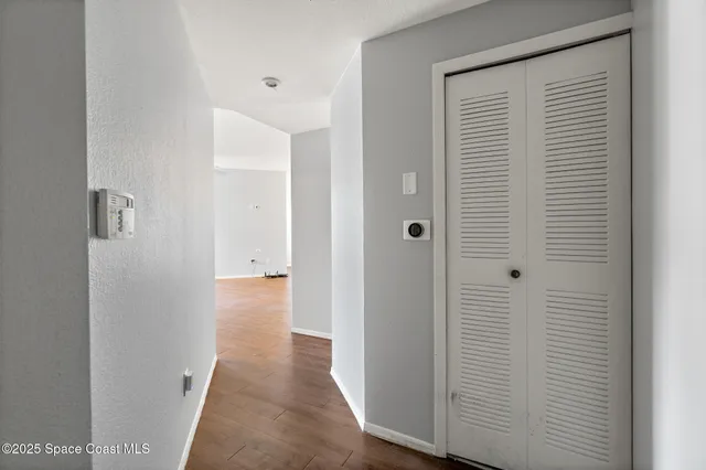 an empty room with wooden floor chandelier fan and windows