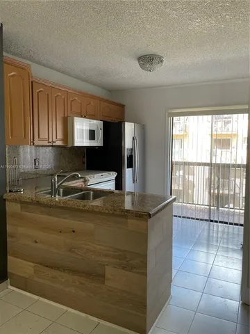 a kitchen with kitchen island sink and large window