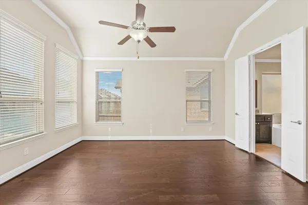 an empty room with wooden floor fan and windows