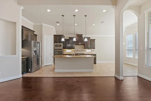 a view of kitchen with kitchen island wooden floor center island and stainless steel appliances