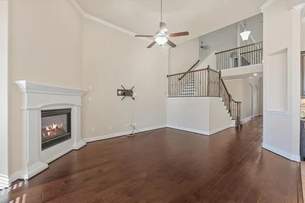 a view of an empty room with wooden floor fireplace and a window