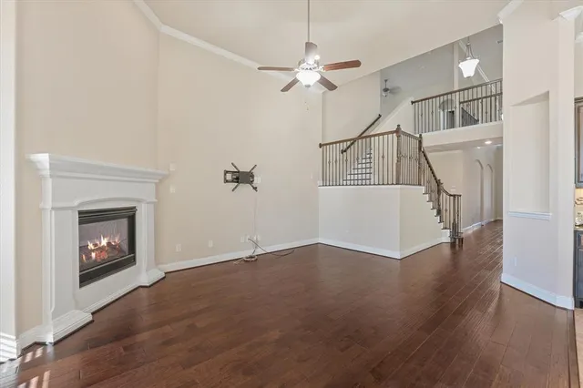 a view of an empty room with wooden floor fireplace and a window