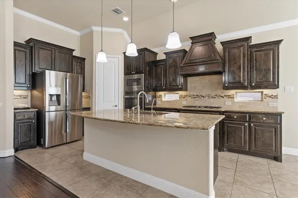 a kitchen with stainless steel appliances granite countertop a sink a stove and a refrigerator