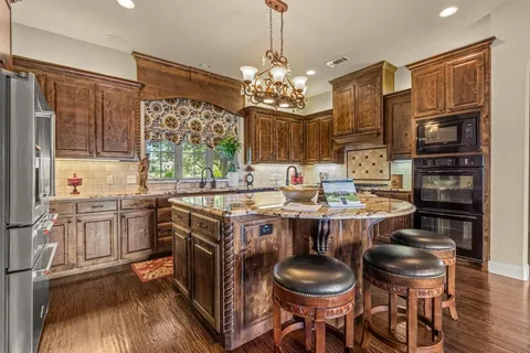 a kitchen with kitchen island granite countertop stainless steel appliances a sink and a refrigerator