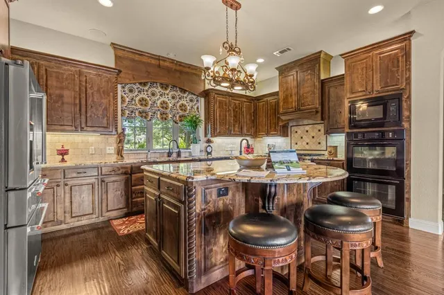 a kitchen with kitchen island granite countertop stainless steel appliances a sink and a refrigerator
