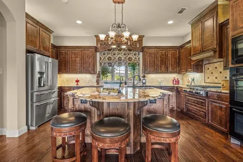 a kitchen with stainless steel appliances granite countertop a kitchen island hardwood floor and a sink