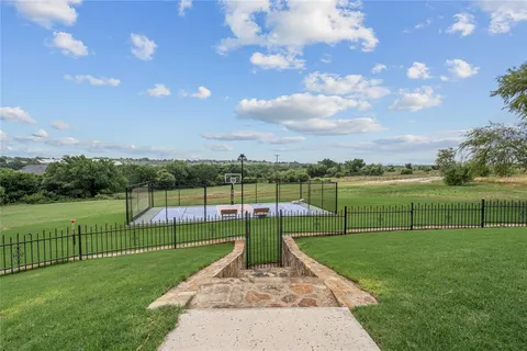 a view of a tennis ground with large trees