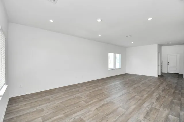 an empty room with wooden floor and window