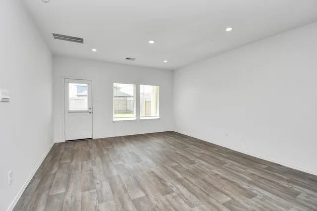 an empty room with wooden floor and windows