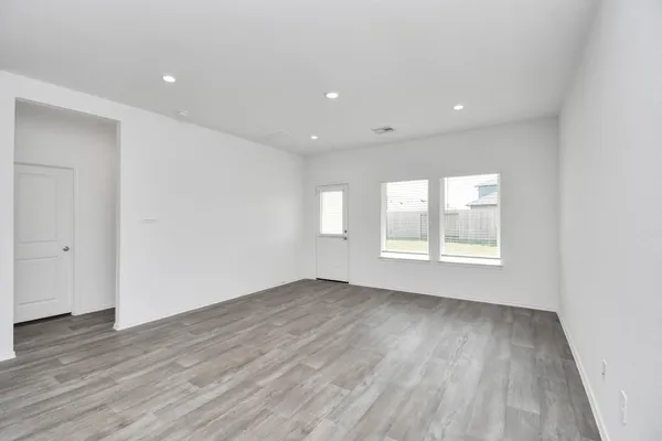 a view of an empty room with wooden floor and window