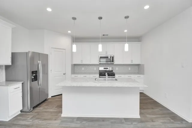 a kitchen with stainless steel appliances granite countertop a sink a refrigerator and a stove