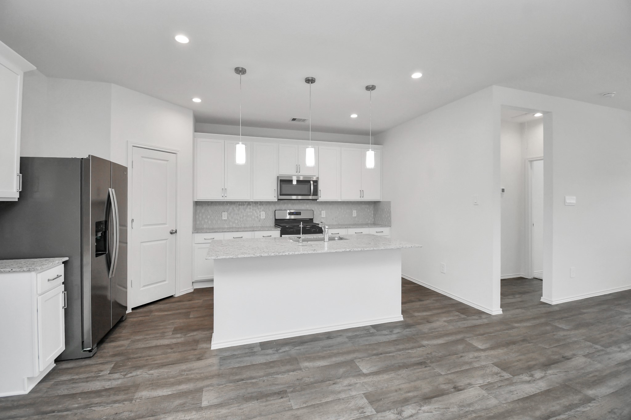 30903 Rockstock Road Fulshear, TX 77441 - Photo 5 of 42 a kitchen with stainless steel appliances granite countertop a refrigerator a sink a stove a microwave and white cabinets with wooden floor