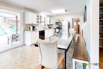 510 Cypress Ridge Road McQueeney, TX 78123 - Photo 22 of 32 a kitchen with stainless steel appliances granite countertop a refrigerator a stove top oven a sink dishwasher and white cabinets next to a window