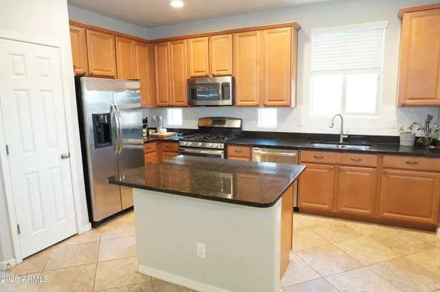a kitchen with stainless steel appliances granite countertop a stove a sink a microwave a refrigerator and cabinets