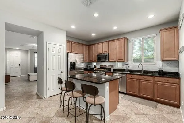 a kitchen with stainless steel appliances granite countertop a stove top oven a sink dishwasher a refrigerator and white cabinets with wooden floor