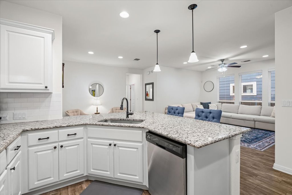 5912 Corrine Lane Austin, TX 78747 - Photo 27 of 27 Kitchen peninsula featuring dishwasher, white cabinetry, and single bin sink overlooking the open floor plan.