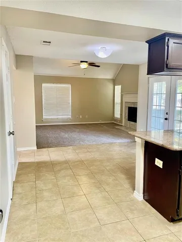 a view of an empty room with kitchen and a window