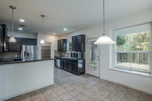 a kitchen with stainless steel appliances granite countertop a stove a sink a refrigerator and a wooden floor