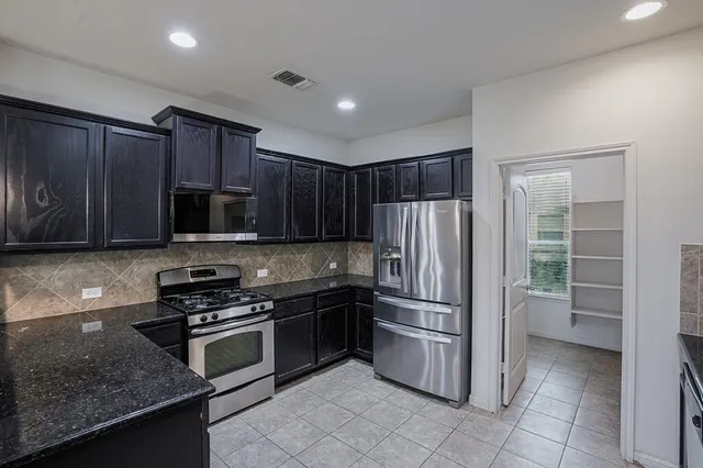 a kitchen with granite countertop a refrigerator and a stove top oven
