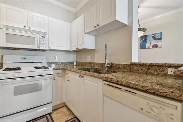 a kitchen with granite countertop white cabinets and white appliances