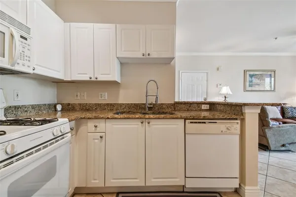 a kitchen with granite countertop white cabinets and white appliances