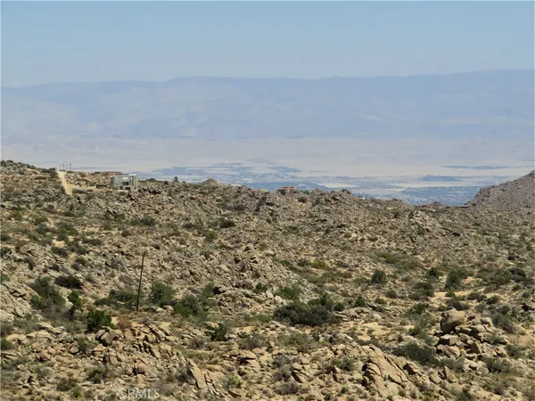 a view of a dry field with mountains in the background