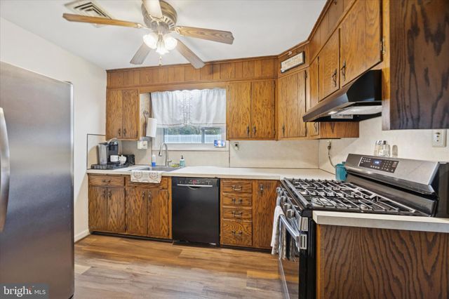 a kitchen with stainless steel appliances a sink a stove a refrigerator cabinets and a window