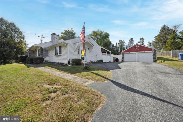 a view of a house with a yard and large trees