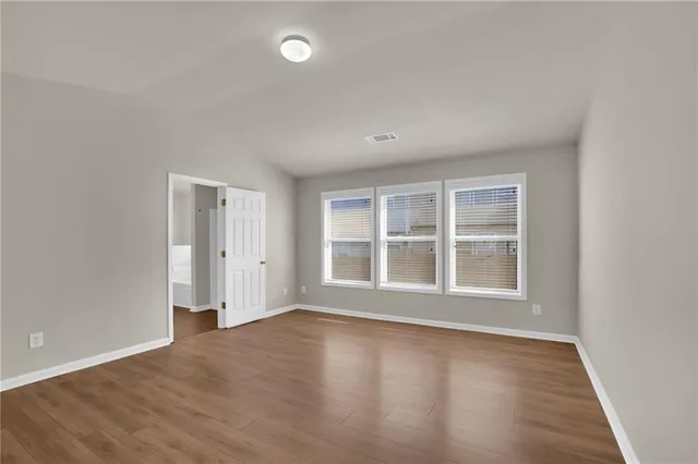 an empty room with wooden floor and windows