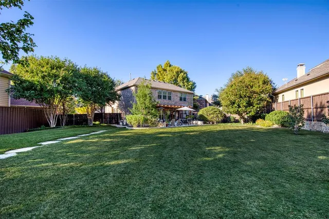 a view of a backyard with table and chairs potted plants and a large tree