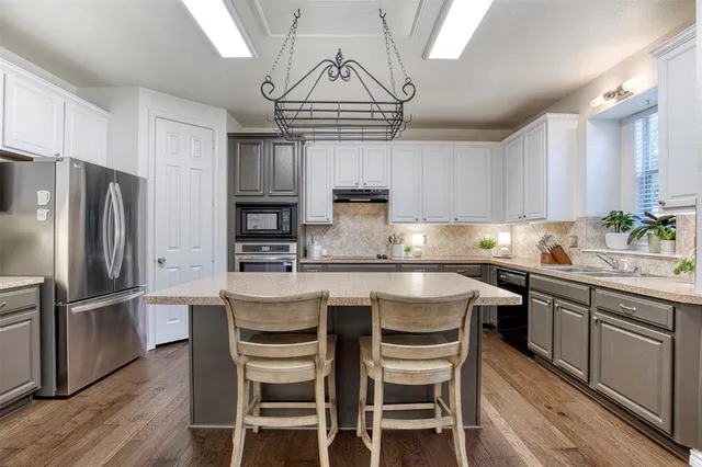 a kitchen with stainless steel appliances granite countertop a dining table chairs refrigerator and cabinets