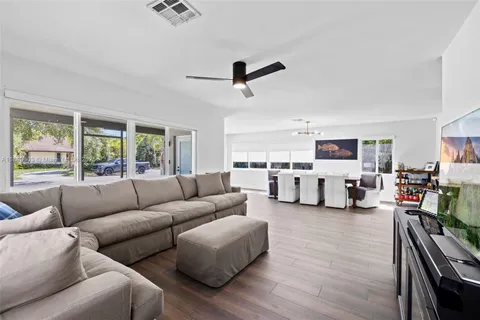 a large living room with stainless steel appliances kitchen island granite countertop a table chairs and a view of living room