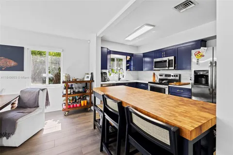 a dining room with stainless steel appliances a table and chairs with wooden floor