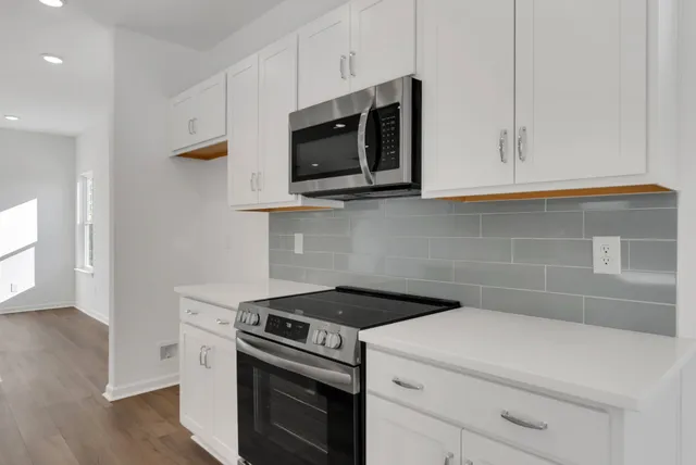 a kitchen with stainless steel appliances granite countertop a table chairs refrigerator and microwave